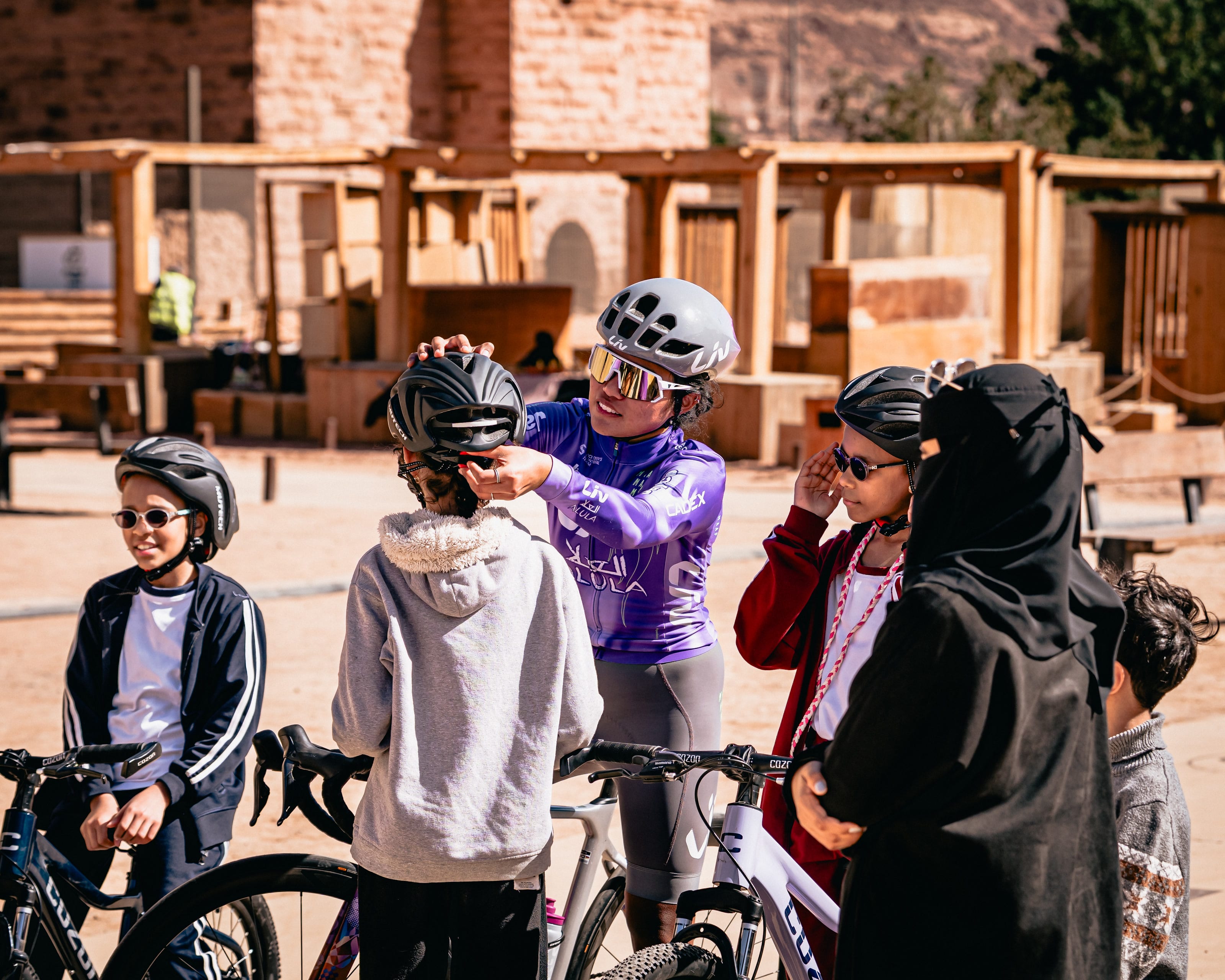 Moroj Adil fitting a helmet for a young rider at a training clinic in AlUla