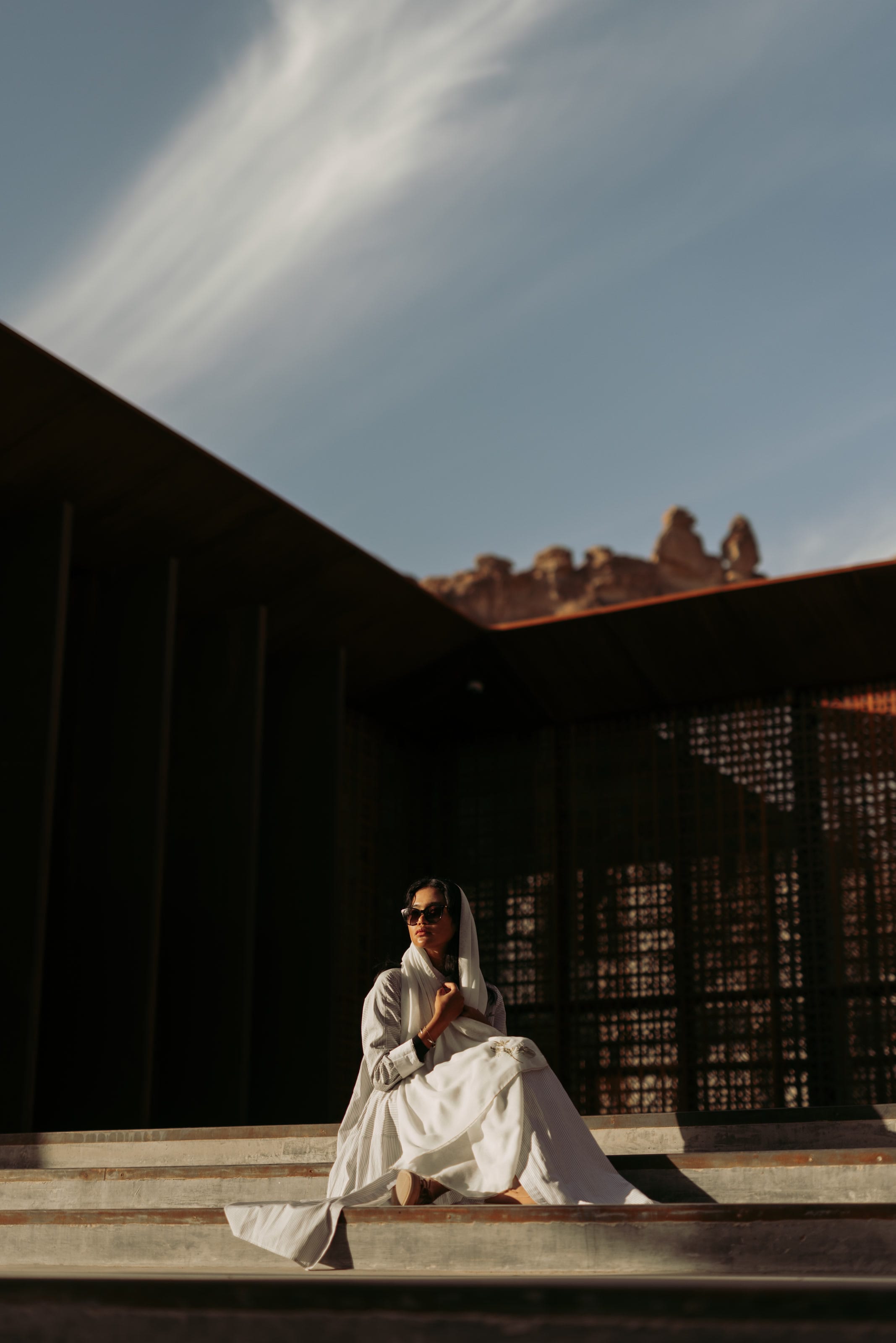 Moroj Adil seated on steps in AlUla, away from the bike