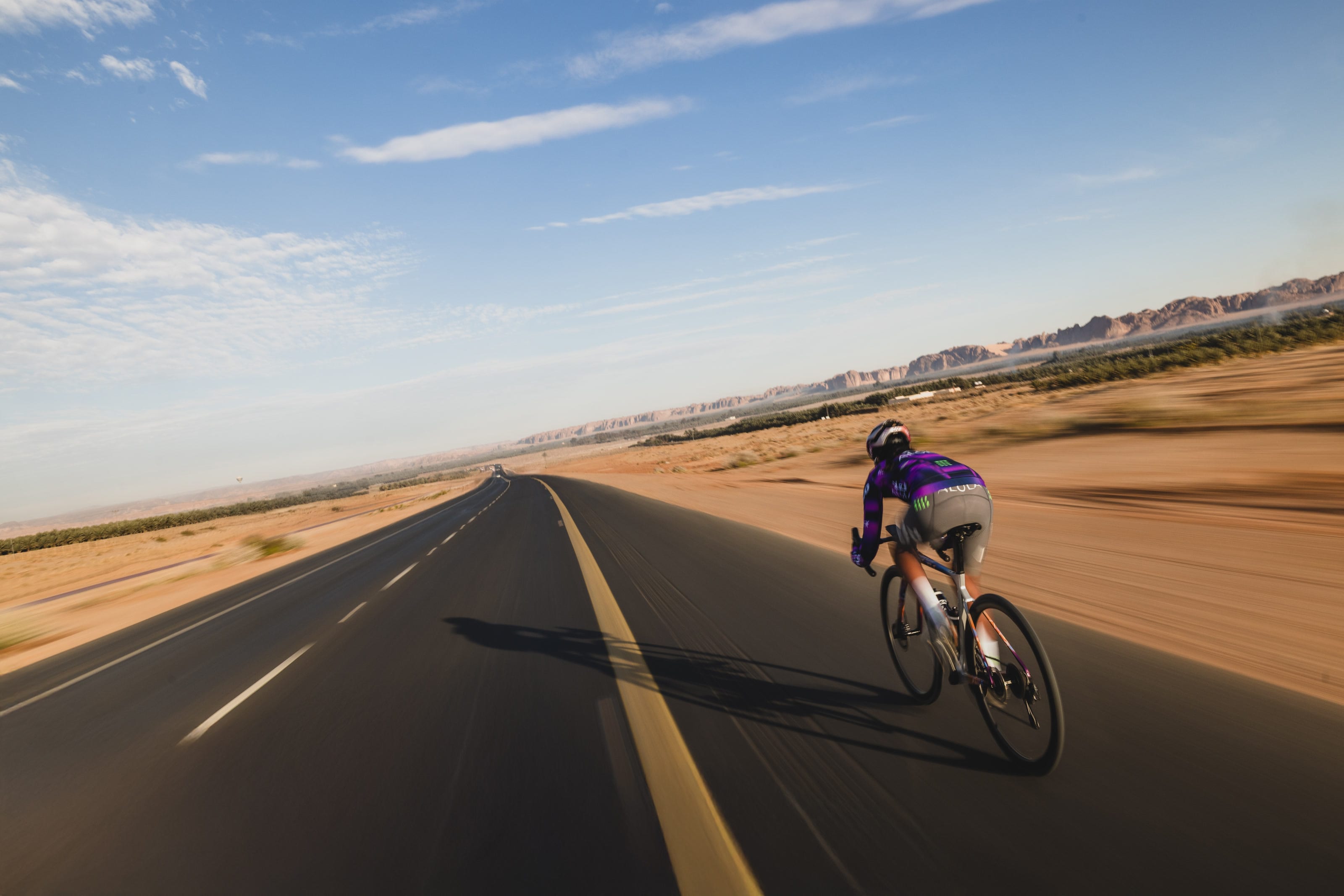 Moroj Adil riding away along a desert road in AlUla